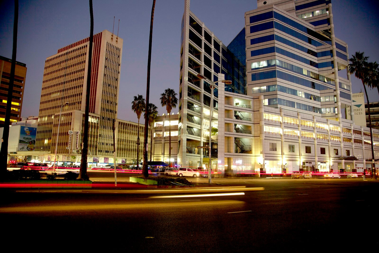 The Harare central business district at dusk, office towers lit against a deep blue sky.